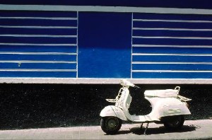 white vespa in front of colorful housefacades